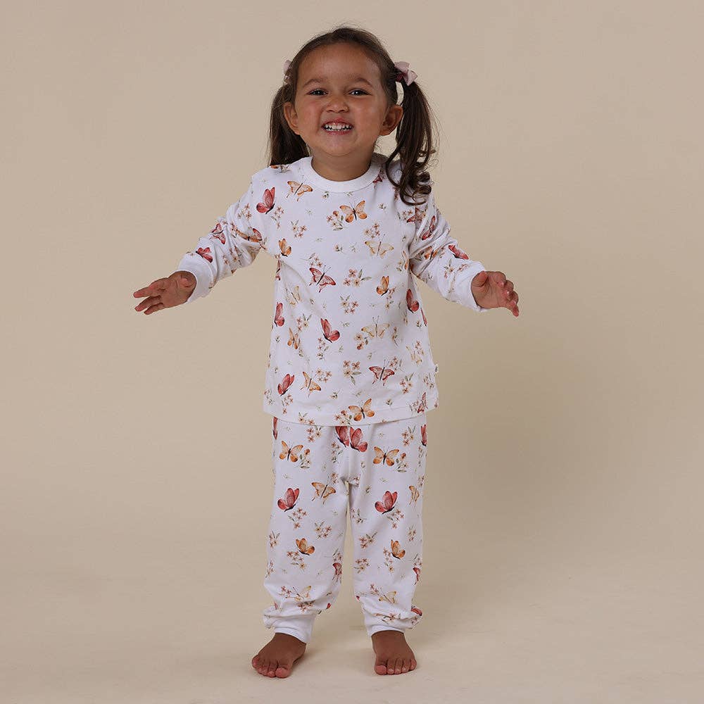 Child wearing a floral and butterfly pyjama set on a beige background