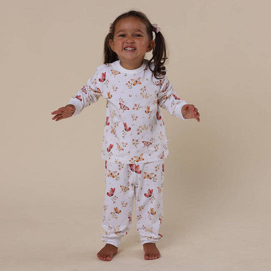 Child wearing a floral and butterfly pyjama set on a beige background